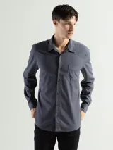 Camisa de manga larga color verde oliva, confeccionada en algodón. Tiene corte clásico, bolsillo en el lado izquierdo del pecho y cierre con botones.