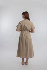 Vestido camisero midi color beige, con cuello camisero, mangas cortas con dobladillo, cierre frontal con botones y lazo para ajustar en la cintura.