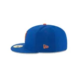 Gorra New Era 59Fifty cerrada, color azul con logo de los New York Mets bordado en naranja en el frente y botón superior naranja.