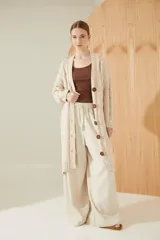 Saco largo tejido en flama color beige, con punto trenzado y desagujado. Lleva botones grabados y detalle de cuero.