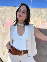 Gargantilla choker con hilo trenzado color blanco, adornada con conchas marinas tipo buzios y medallitas bañadas en oro y acero quirúrgico. Se cierra con cadena de acero quirúrgico y ganchito para ajustar el largo.