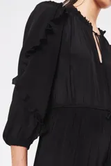 Vestido midi negro con escote en V, mangas largas con volados en los hombros, cintura con lazo ajustable y falda escalonada con volados.