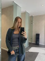 Campera tejida con textura vanizada a rayas verticales en color lila y negro, con cierre frontal y cuello alto.