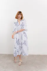 Vestido largo blanco con estampado de hojas azules, corte suelto, escote en V, mangas 3/4 amplias y bolsillos laterales.