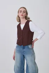 Chaleco negro de poliéster con escote en V y cierre frontal de botones. Diseño holgado.