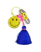 Colgante para celular con correa de silicona negra y dijes colgantes: smiley con strass, flor rosa, borla azul y cadena metálica.