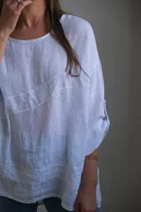 Blusa blanca de lino con mangas 3/4 y detalle de bordado calado en el frente y ruedo.
