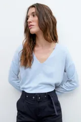 Sweater de tejido liso color celeste claro, con escote en V y mangas largas.