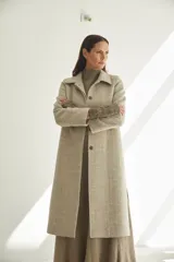 Tapado largo con cuello solapa y corte recto, color gris claro. Tiene cierre frontal con botones ocultos, tajos laterales y bolsillos escondidos en el corte lateral. Está forrado y confeccionado en lana fina sin teñir, diseñada exclusivamente por Don Baez. Hecho 100% en Uruguay.