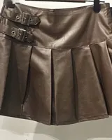 Minifalda marrón de cuero sintético con diseño tableado y dos correas decorativas con hebillas plateadas en la cintura.