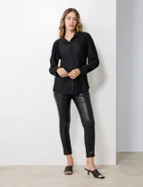 Camisa negra de satén plisado con cuello con solapa y abertura central con botones.