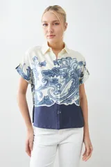 Camisa de manga corta con estampado paisley en tonos azul y blanco, con cuello clásico y cierre con botones.