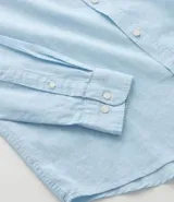 Camisa celeste de lino con cuello camisero, abotonadura frontal y mangas largas.