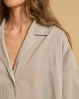 Camisa color gris claro, de manga 3/4, tela ligera, cuello camisero con solapa y escote en V.