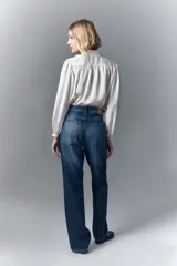 Jean de tiro alto y calce recto, confeccionado en denim azul rígido. Presenta un diseño de hotfix brillante en forma de guitarra en el frente de la pierna derecha.