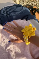 Coletero con elástico forrado en tela estampada a rayas amarillas y blancas, con aplique de sol tejido a crochet en hilo amarillo.