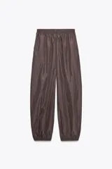 Pantalón bombacho marrón de nylon con cintura elástica, bolsillos laterales ocultos y bajo abullonado con elástico.