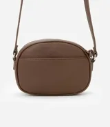 Cartera tipo camera bag pequeña, color marrón camel, de forma ovalada con superficie texturizada. Cuenta con correa ajustable larga, cierre principal con cremallera dorada y un pequeño bolsillo frontal con cremallera.