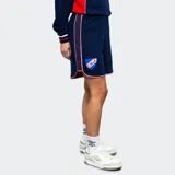 Short deportivo azul marino con cintura elástica y cordón ajustable. Presenta una franja lateral blanca con un fino borde rojo. Logo de Umbro bordado en el muslo izquierdo.