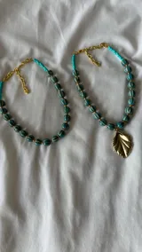 Collar corto de cuentas turquesas con rayas horizontales blancas y separadores dorados.