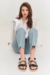 Sandalias de cuero color blanco con doble tira plateada con velcro, base negra y hebilla plateada.