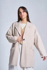 Tapado gris oscuro de corte oversize, con solapa clásica, hombros caídos, cierre con un botón central y bolsillos laterales funcionales.