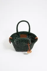 Bolso tipo tote de mimbre color marrón oscuro, con doble asa corta y correa de cuero marrón. Incluye dije circular dorado con letras grabadas.