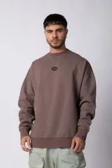 Buzo marrón de frisa con corte oversize, cuello redondo y logo VCP bordado en el pecho. Puños y ruedo acanalados.