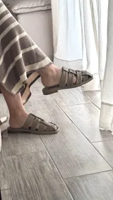 Sandalias bajas color marrón claro con tiras anchas de cuero entrelazadas.