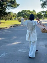Camisa larga con punto smock y pollerín tipo blazer, con estampado floral en tonos beige y detalles de flecos rojos.