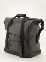 Bolso tipo duffel verde militar con base y detalles en negro. Tiene doble asa de mano y correa de hombro ajustable y extraíble. Cuenta con dos bolsillos frontales con cierre y logo de la marca en la parte inferior.