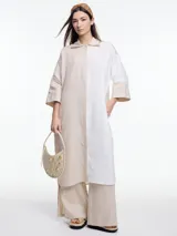 Pantalón de lino negro con elástico en la cintura, tiro medio y calce relajado. Lleva tiras en color gris aplicadas a los laterales, que quedan sueltas en la parte inferior y pueden anudarse.