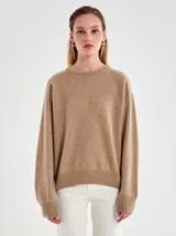 Sweater de punto liso color camel/beige, con cuello redondo y calce relajado. Presenta terminaciones acanaladas en puños y ruedo.