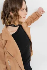 Chaqueta negra tipo biker de gamuza sintética con cuello solapa y manga larga con trabillas en los hombros. Tiene bolsillos delanteros con cremallera metálica y cierre frontal con cremallera.