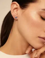 Pendiente tipo piercing en forma de ojo, de aleación de metales bañada en plata con cristal de Swarovski color light sapphire.