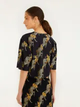 Remera corta negra con estampado de cebras en tonos dorados.