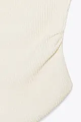 Top blanco de cuello barco y manga sisa. Tiene detalle de drapeado lateral y bajo asimétrico.