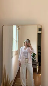 Camisa rosa a rayas verticales blancas, de lino, con cuello clásico, cierre frontal con botones y mangas largas.