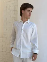 Camisa blanca de lino, de manga larga con puños doblados, cuello clásico y botones frontales.