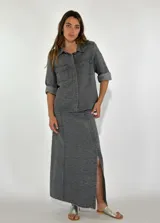 Chaqueta color gris con textura, de corte recto, cuello camisero, cierre frontal con botones, mangas 3/4 con puños arremangados, dos bolsillos de parche en el pecho y ruedo recto.