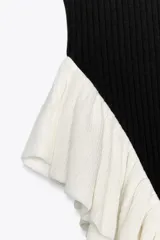 Top de punto negro con escote redondo, tirantes anchos y volantes blancos en el bajo.