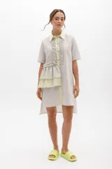 Vestido camisero a rayas con cuello y cartera en tono lima claro, volados frontales y laterales. De calce relajado y mangas cortas. Fabricado en Uruguay.