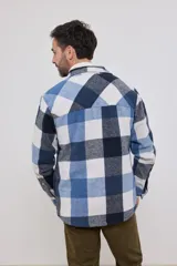 Sobrecamisa de hombre con diseño a cuadros en tonos marrón, beige y blanco. Confeccionada en tejido peludito suave, con cuello clásico, cierre frontal con botones, bolsillo superior y mangas largas con puños abotonados.