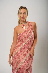 Vestido midi de crochet con diseño de ondas en tonos rojo, rosa y beige. Tiene un solo hombro y tajos laterales.