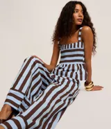 Pantalón de cintura alta, confeccionado en tricolina de algodón, con cierre tradicional, pliegues y rayas verticales en azul claro y marrón.