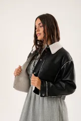 Campera corta negra de cuero sintético con cuello y forro de piel sintética blanca.