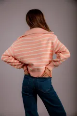 Sweater de punto color beige con rayas horizontales blancas, cuello polo con cierre de cremallera y mangas largas.
