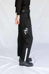 Pantalón de trabajo negro de gabardina con tiro medio, cintura ajustable, cinta utilitaria trasera, bolsillo para metro bordado y cinta reflectiva en los bajos.