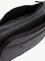 Riñonera negra de poliéster con acabado liso y logo metálico de Tommy Hilfiger en el frente. Cuenta con cierre de cremallera, cartera ajustable, compartimento principal y bolsillo exterior con cremallera.