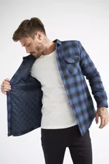 Sobrecamisa de viyela para hombre con estampado de cuadros en rojo y negro. Presenta cierre frontal con botones, bolsillos en el pecho con solapa y botón, y un interior capitoneado para mayor abrigo. Cuenta con un logo en grifa de cuero.